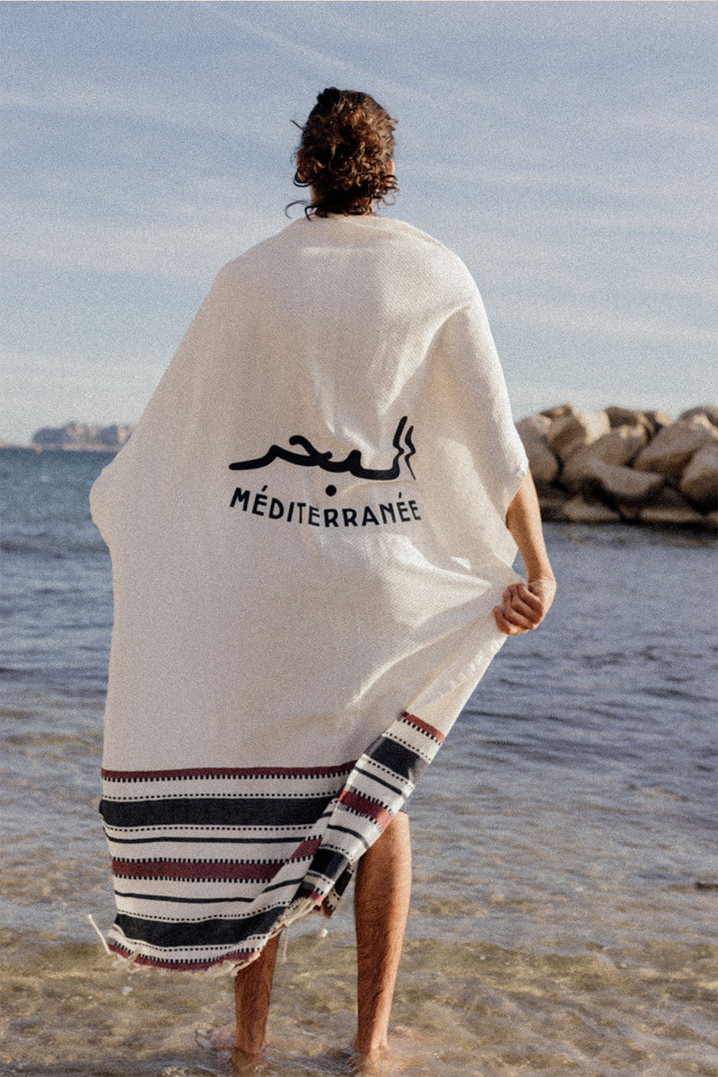 Homme en bord de mer avec sa fouta LYOUM sur le dos.